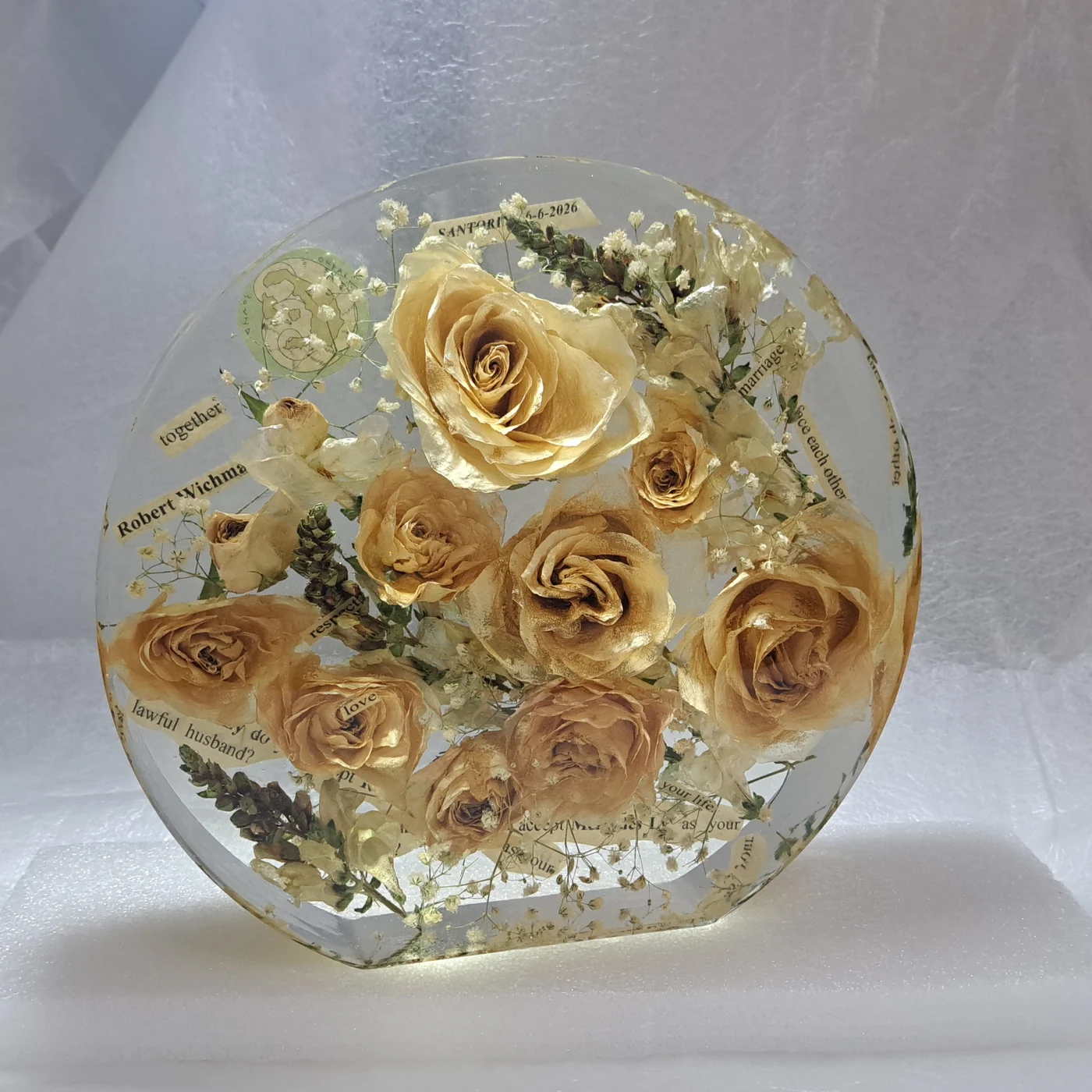 Cream roses and wedding vows preserved in a round resin casting